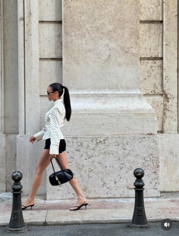 Camicia bianca a pois con shorts neri e una borsa